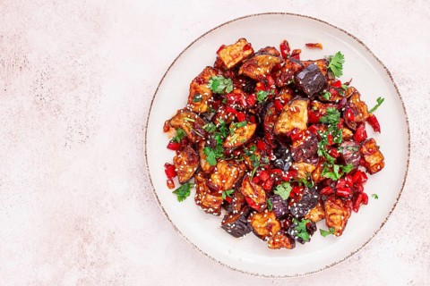 Fried eggplant, Chinese style, in sweet and sour sauce, with pepper and sesame seeds. on a white