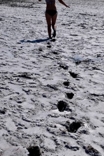 Woman walking along the dry bottom of a salt lake, rear view. Taman, Krasnodar Krai, Russia