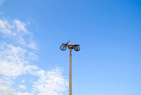 Motorcycle on the pedestal. A light motorbike on a pole, put up as a dummy or a monument.