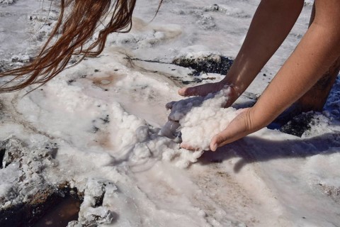 Hands girls taking on the wet salt from the puddles. Taman, Krasnodar Krai, Russia