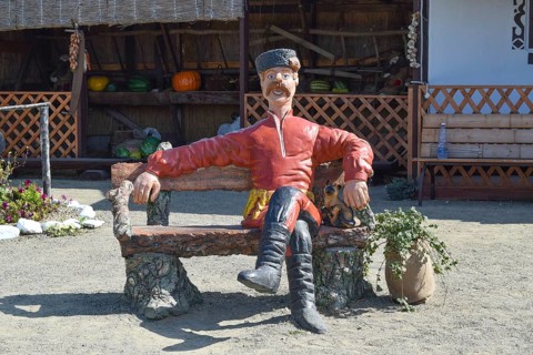 Statue in Cossack fur hat sitting on a bench with a cat. Taman, Krasnodar Krai, Russia