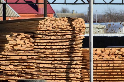Warehouse of building materials, wood planks stacked under a canopy. Atyrau, Kazakhstan