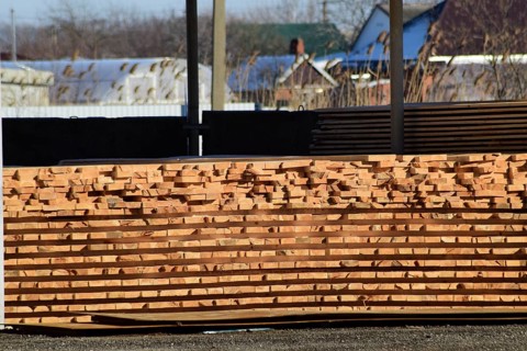 Warehouse of building materials, wood planks stacked under a canopy. Atyrau, Kazakhstan