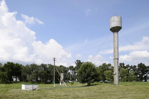 Silver Water Tower among green grass and trees. Atyrau, Kazakhstan