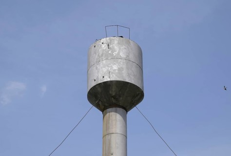Silver Water Tower among green grass and trees. Atyrau, Kazakhstan