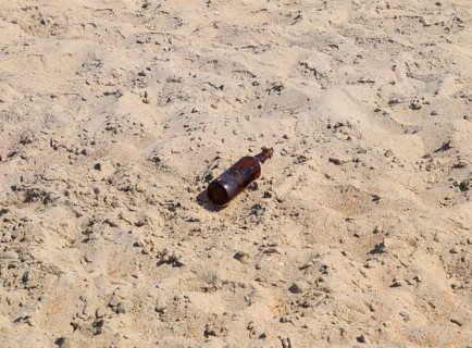 An empty bottle of beer is lying on the sand. Golubitskaya, Russia