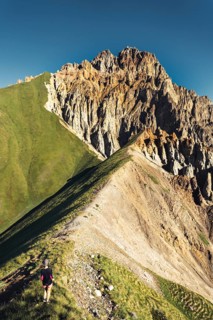 Hiker walking along narrow ridge trail at Kabarjina Mountain in Kazbegi National Park Georgia with