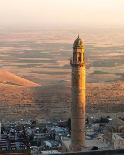 Historic Ulu Cami minaret in Mardin Turkey illuminated by sunset, overlooking ancient Mesopotamian