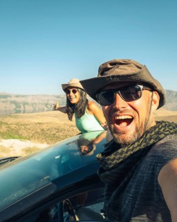 Happy travelers on summer road trip with rental car, symbolizing freedom, travel insurance, car
