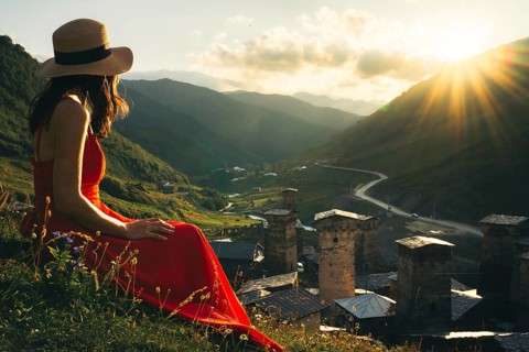 Tourist woman in red dress enjoy view of Ushguli village in Georgia