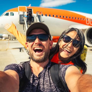Happy couple of tourists boarding outside to plane at the airport - Happy man and woman having