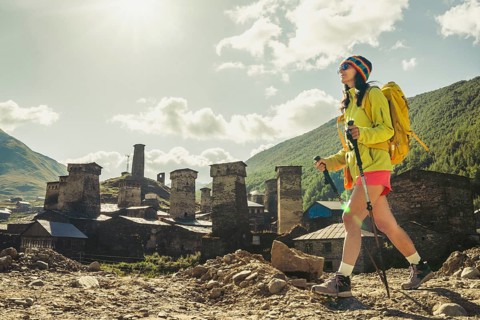 Traveler hiking with backpack and poles in Ushguli, Svaneti mountains, wellness trekking and