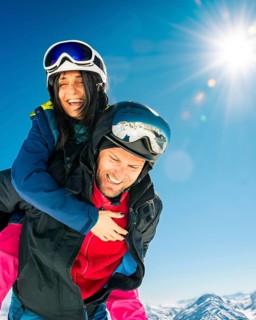 Romantic happy skiers couple in love having fun together playing in mountains piggybacking at
