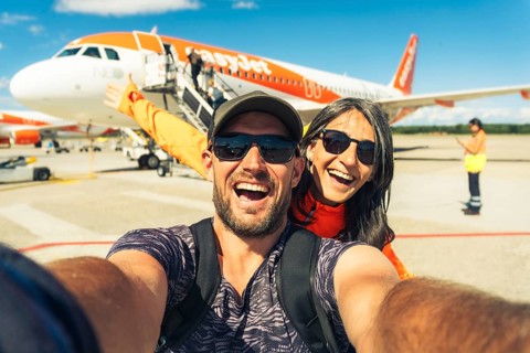 Milan, Italy - 12th august, 2025: happy smiling couple taking selfie in front of EasyJet airplane