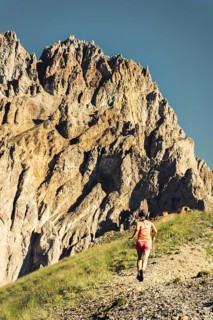 Sporty Female athlete trail runner running in motion mid air in alpine mountains, adventure fitness