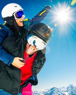 Happy young caucasian skiers couple in love having fun together playing in mountains piggybacking