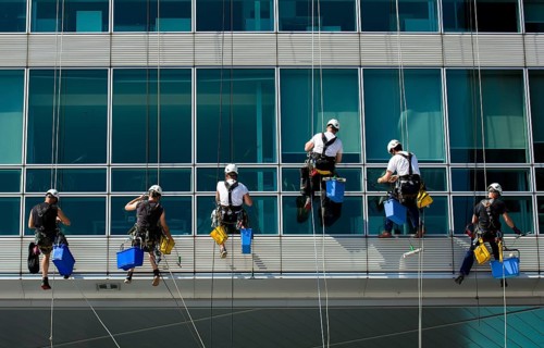 Team Of Climbing Workers In Climbing Equipment On Office Building Cleaning Windows, Vienna, Austria