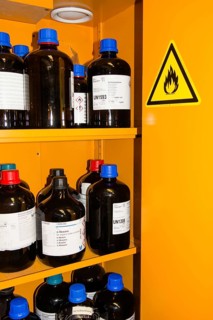 Flammable Chemicals In Bottles With Different Size in Orange Protection Cabinet, Marked With A