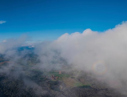 A far-reaching view of Germany's green landscape, surrounded by clouds. The sky is blue and clear.
