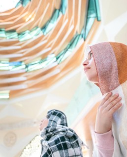 Muslim young millenial girls with scarfs during the pray in modern Marmara mosque in Istanbul.