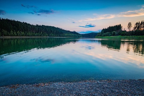 Reflecting water in the reservoir against an evening forest backdrop and a peaceful atmosphere,