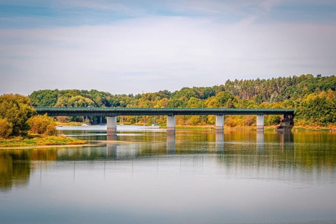 Bridge over a quiet reservoir with wooded shores and clear skies, Zeulenrodaer Meer reservoir,
