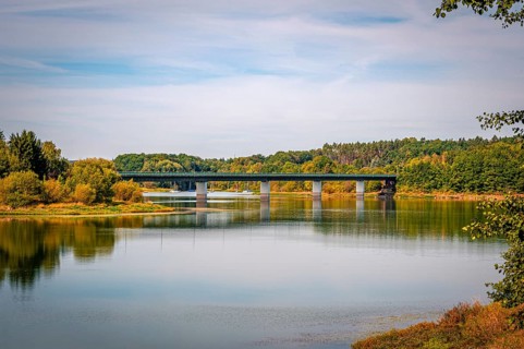 View of a bridge surrounded by green trees and a clear sky, Zeulenrodaer Meer reservoir,