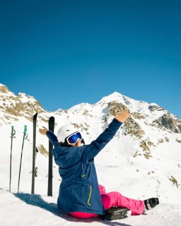 Young happy caucasian woman pose with skis arms outstretched in high mountains. Get away skiing