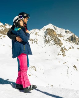 Young caucasian couple pose hug enjoying looking at snowy mountains range in winter. Get away