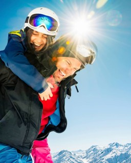 Romantic happy skiers couple in love having fun together playing in mountains piggybacking at