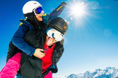 Romantic happy skiers couple in love having fun together playing in mountains piggybacking at