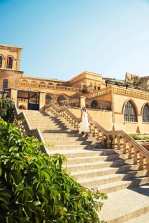 Traveler woman in white dress walking stairs of historic building - visit Mardin museum in old city