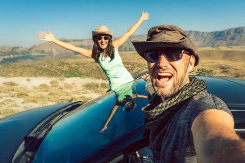 Happy travelers taking selfie photo on summer road trip with rented car in Turkey, symbolizing