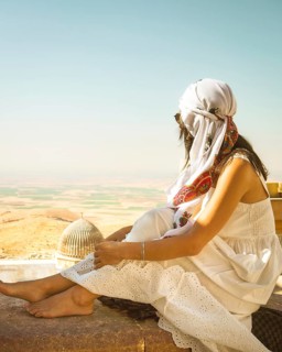 Traveler woman or tourist wear white dress sitting near Great Mosque of Mardin overlooking vast