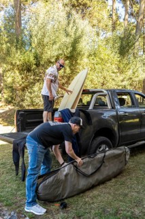 Two men packing surfboards into a truck