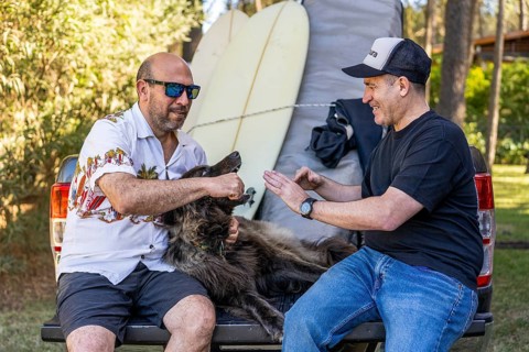 Two men and their dog relaxing on a pickup truck