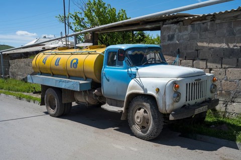 A blue and yellow petrol tanker stands by the roadside in a village, Armenia