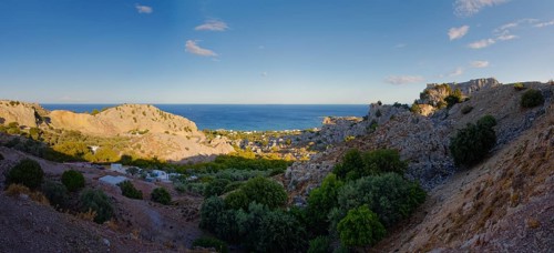 Panoramic view of the hilly coastal landscape of Stegna with clear blue sky and natural vegetation,