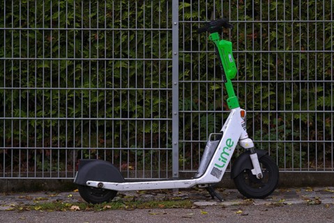 On the side of the road, fence, parked e-scooter, electric scooter, scooter, in the bike rental of