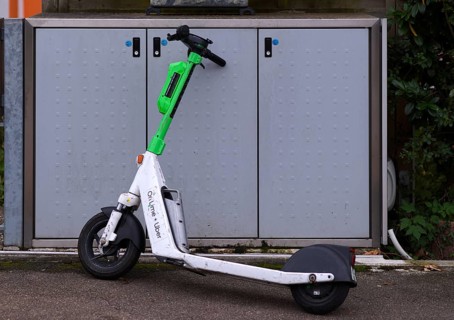 On the pavement, pavement, container for waste bins, parked e-scooter, electric scooter, scooter,