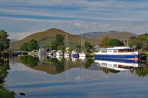Water reflections of boats in the harbour in front of picturesque mountains, Caledonian Canal,