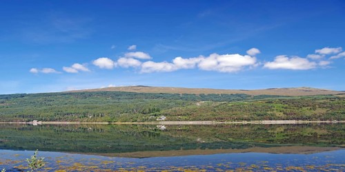 A clear lake reflects the surrounding mountains and cloudy sky, Caledonian Canal, Fort William,