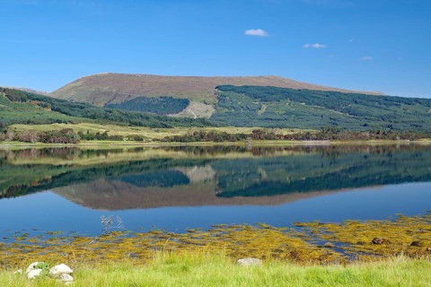 A loch with a clear reflection of mountains under a bright blue sky, Loch Eil, Scotland, Great