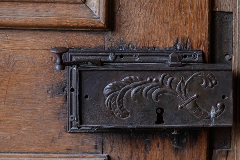 Detail of an old metal lock on a carved wooden door frame, Hesse, Germany