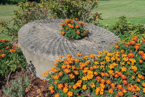 Old millstone as decoration in a flower bed, Münsterland, North Rhine-Westphalia, Germany