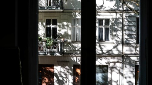 View through a window to an opposite facade of a multi-storey residential building with classical