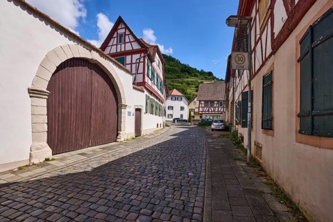 Old town, alley, cobblestone pavement, historic half-timbered houses, wall, access gate, blue sky,