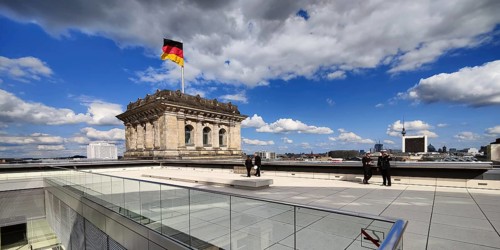 Roof terrace with a German flag in the wind on one of the corner towers of the Reichstag building,
