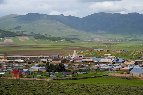 A small village in a green mountain landscape with scattered houses and fields, Yazidi temple, Rya