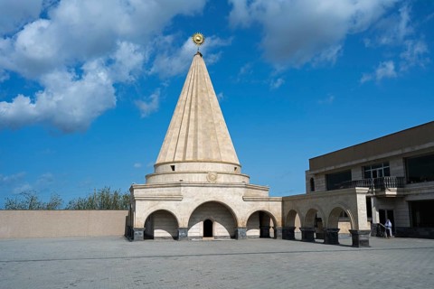 A large stone mausoleum with a dome against a clear blue sky, Yazidi temple, Shekhubekir,